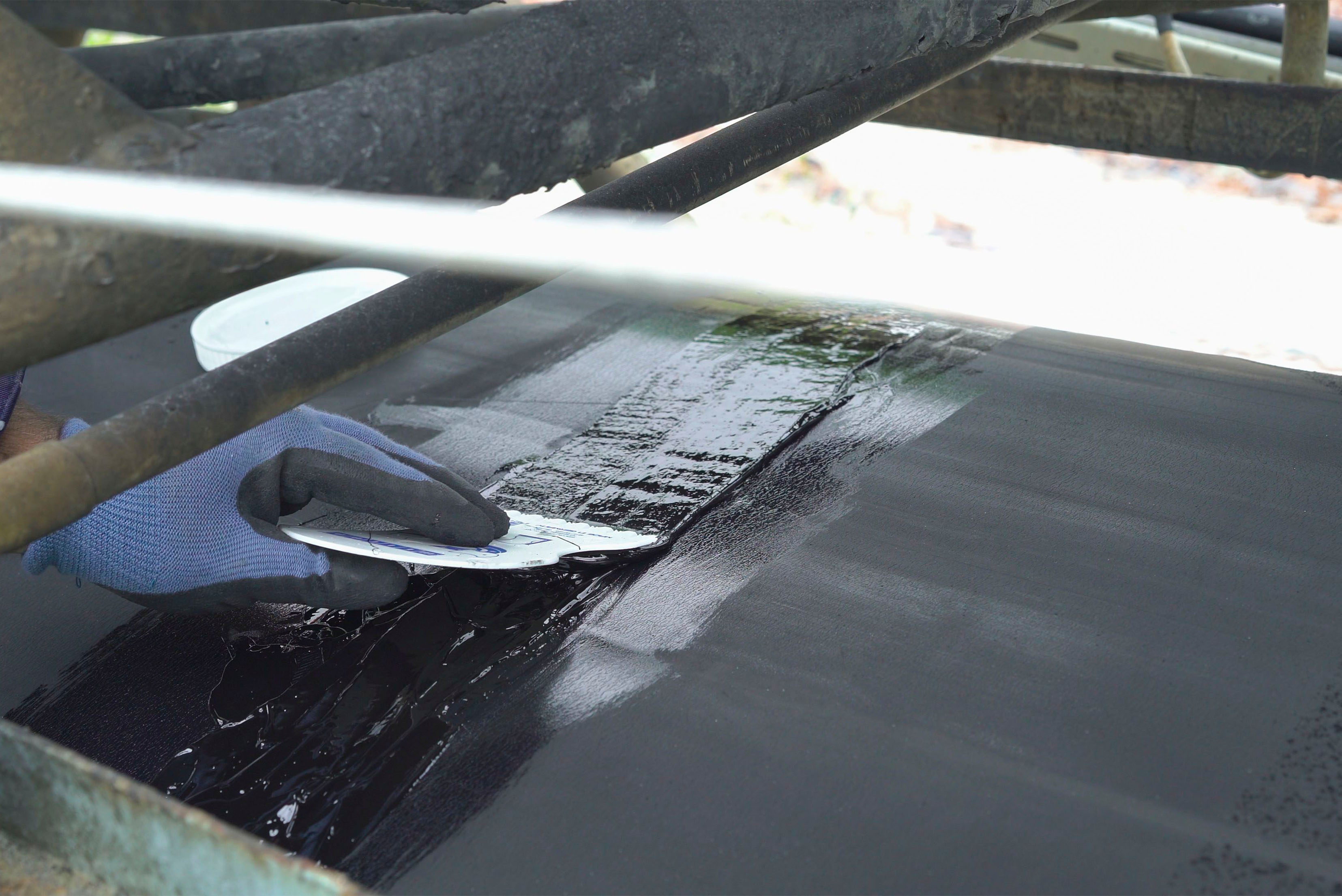 schwarze Masse wir auf Förderband gestrichen