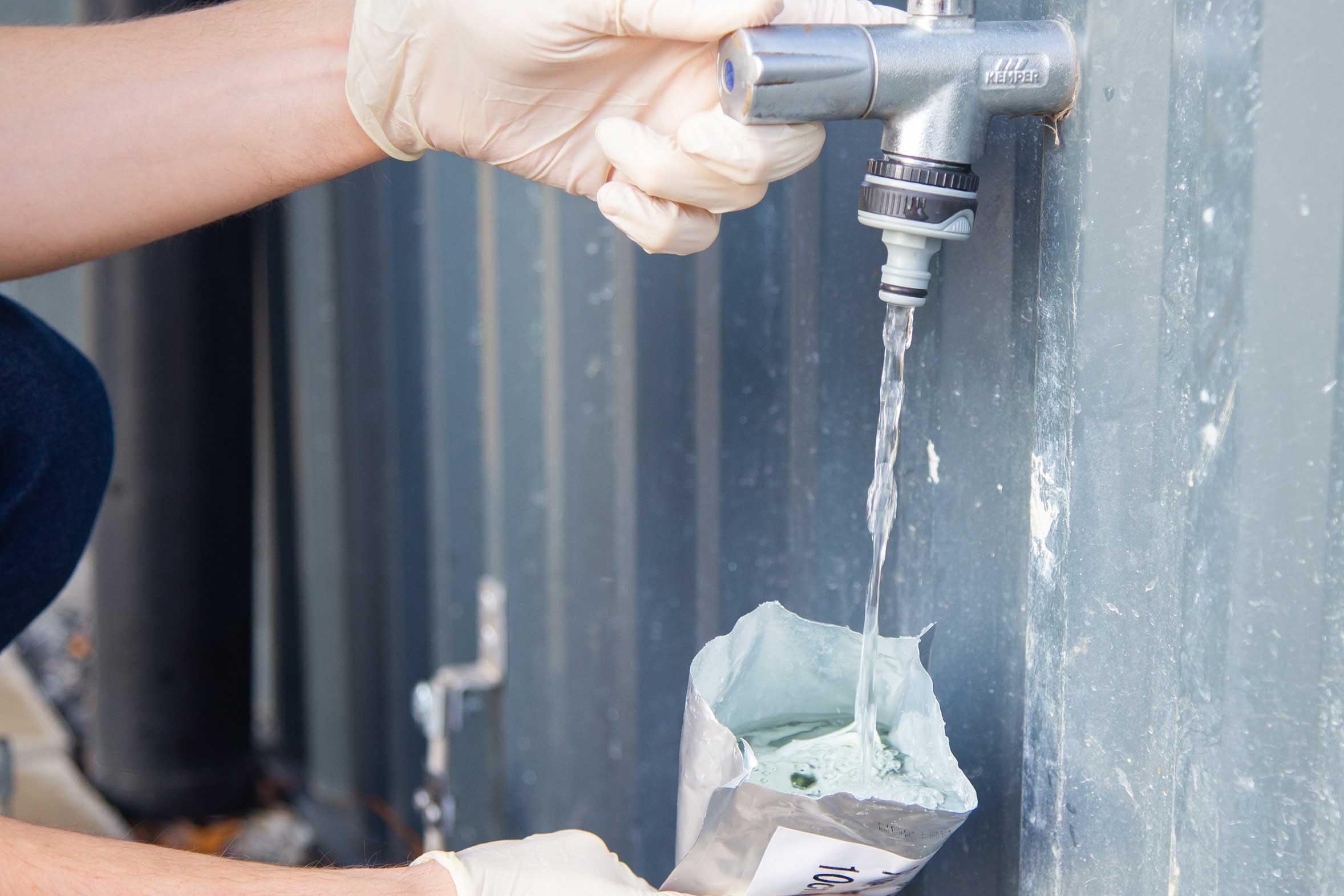 Beutel wird aus einem Wasserhan mit Wasser befüllt