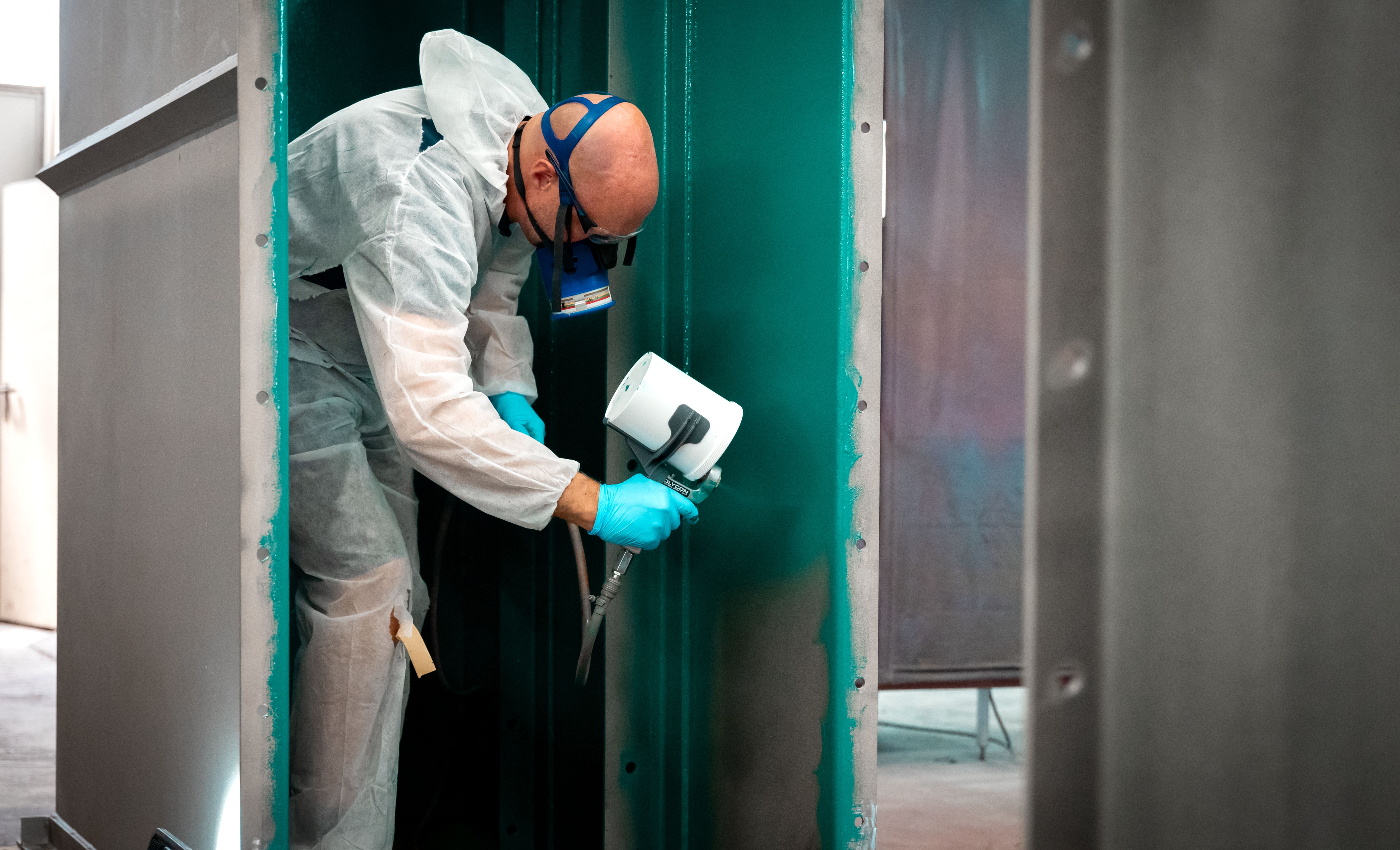 Ein Mann mit Maske sprüht eine grüne Kontrollschicht auf