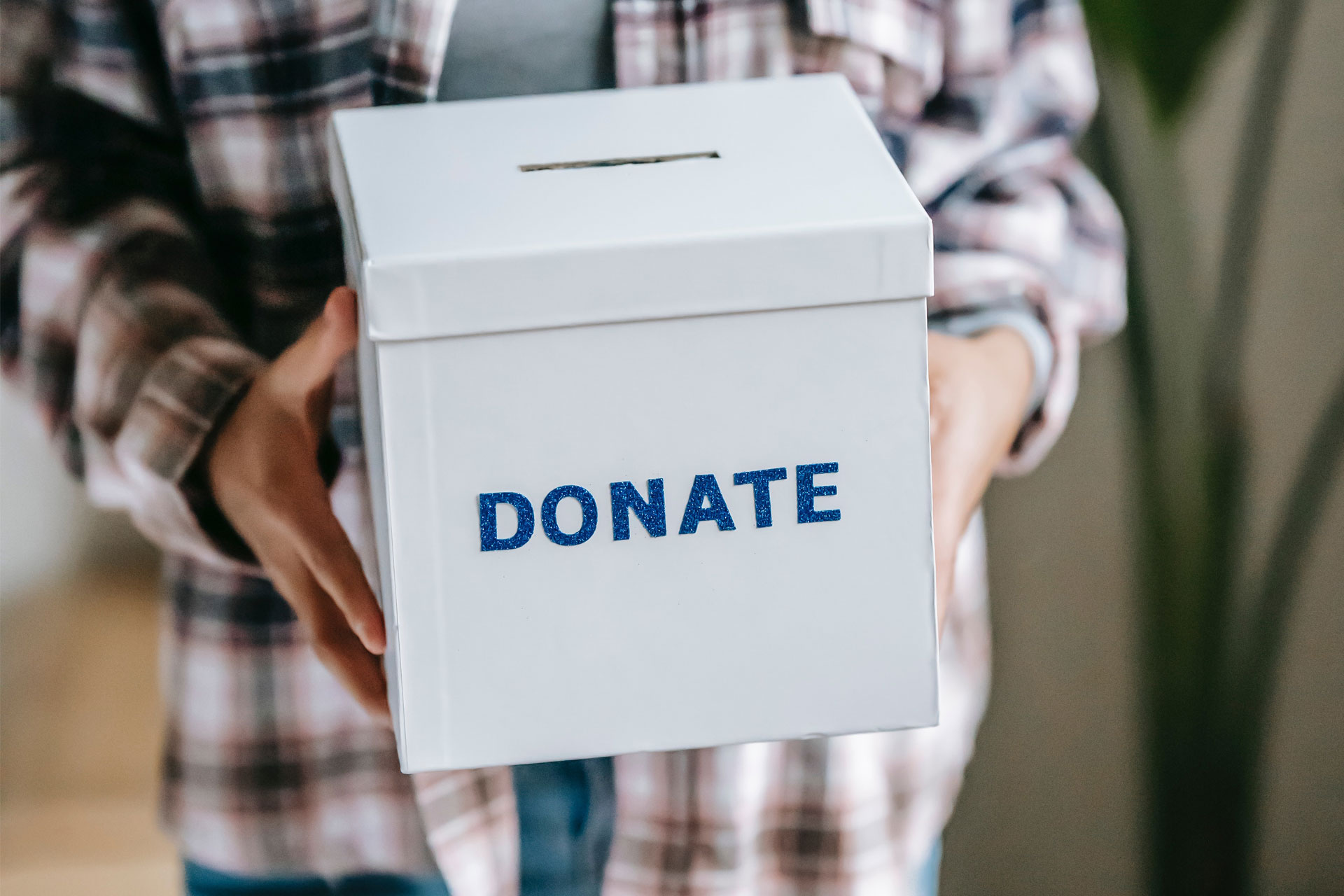 spenden-soziale-projekte Jemand hält eine Pappbox in der Hand, auf der in blau "Donate" steht