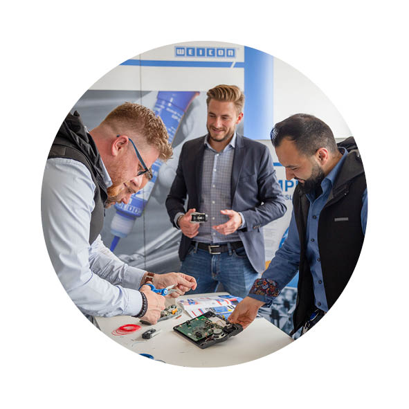 Vier Männer stehen in einem Besprechungsraum und testen Abisolierwerkzeuge aus