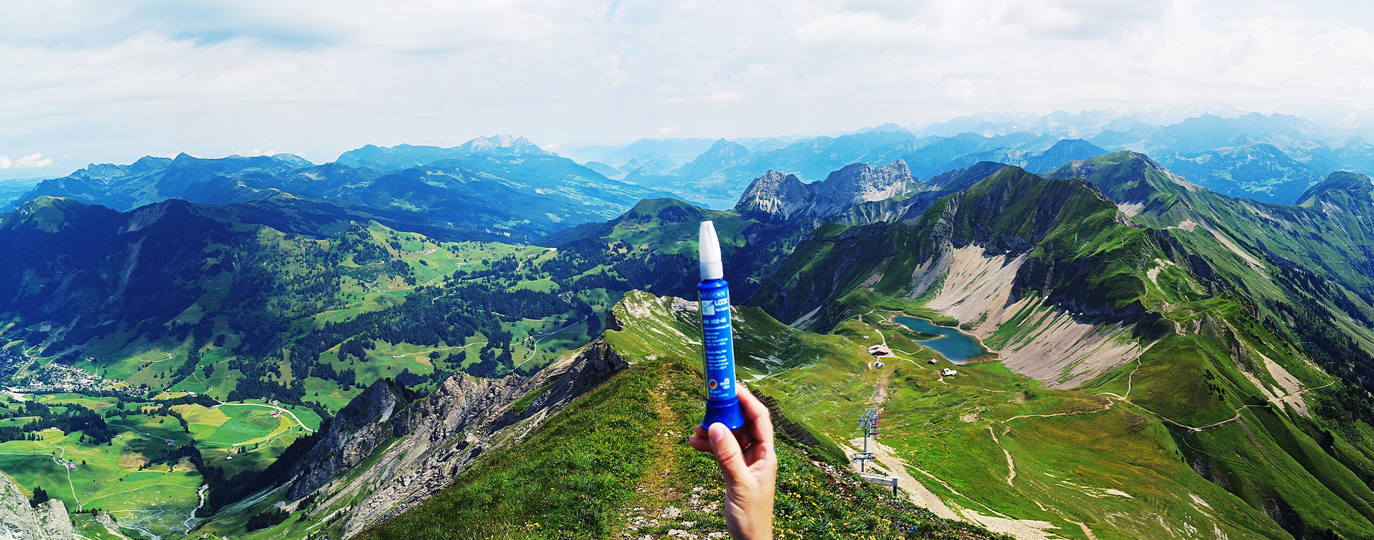 Nachhaltigkeit Berge sind im Hintergrund, vorne hält eine hat eine Klebstofftube von Weicon in der Hand