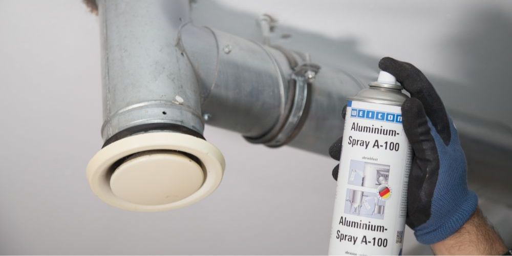 Aluminium-Spray wird auf Rohr gesprüht