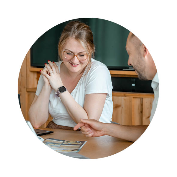 Eine Frau und ein Mann sitzen in einem Besprechungsraum am Schreibtisch und schauen in einen Flyer