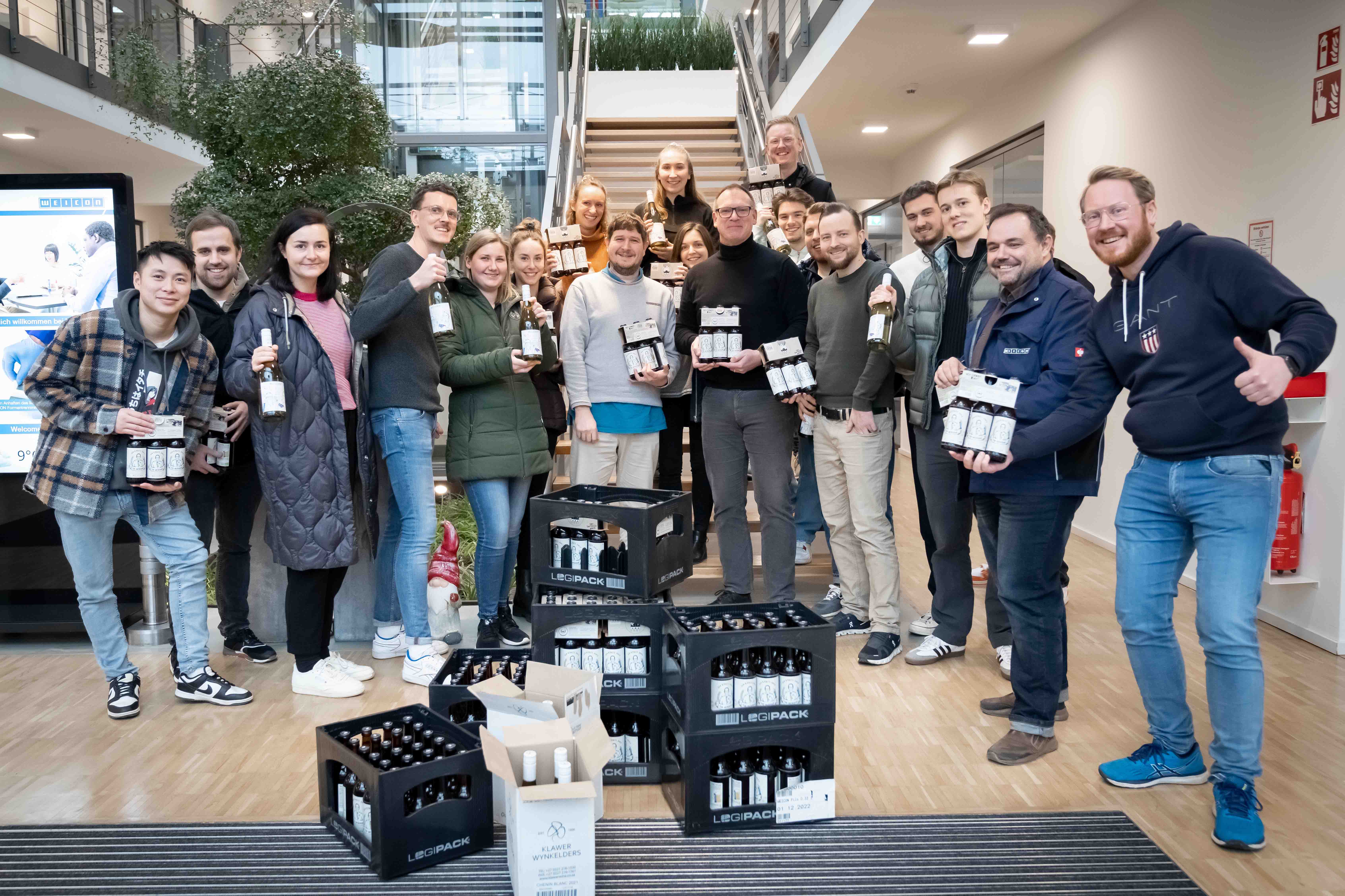 Gruppe von Menschen in einem Bürogebäude, die Wein oder Sekt in der Hand halten